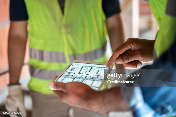 construction site engineer reviewing blueprints on digital tablet - flat inspection stock pictures, royalty-free photos & images