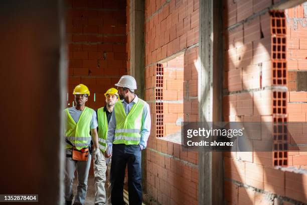 three engineers walking across the construction site. - project manager stock pictures, royalty-free photos & images