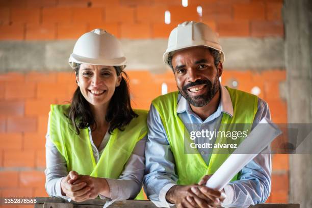 portrait of a two happy construction workers at building site - project manager stock pictures, royalty-free photos & images