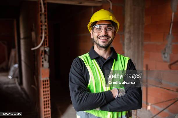 portrait of a confident young man working at construction site - man wearing helmet stock pictures, royalty-free photos & images