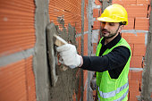 Mason worker plastering cement on brick wall