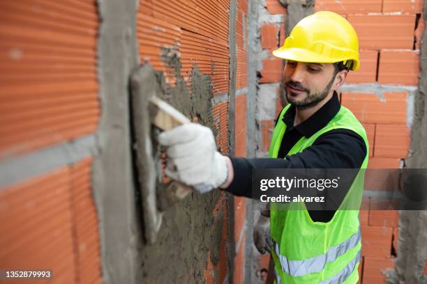 mason worker plastering cement on brick wall - drywall finishing stock pictures, royalty-free photos & images