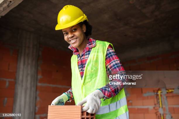 porträt einer jungen maurerin, die auf der baustelle arbeitet - brick layer stock-fotos und bilder
