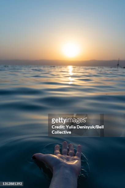 a hand stretches toward the sun in the dead sea, jordan - hand with bell stockfoto's en -beelden