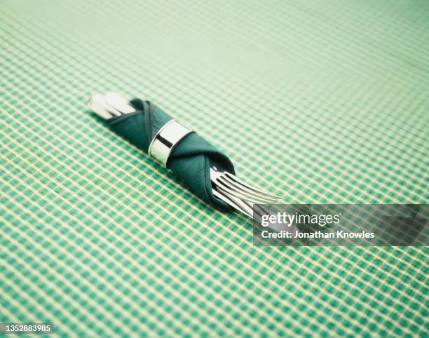 knife and fork wrapped in green napkin with napkin ring - serviettenring stock-fotos und bilder