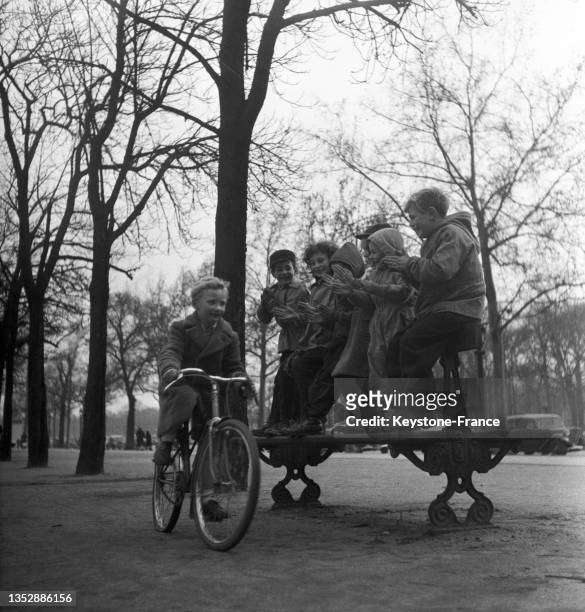 Enfant à vélo jouant à la course des Six jours dans le jardin des Champs-Elysées, le 2 mars 1951, à Paris.