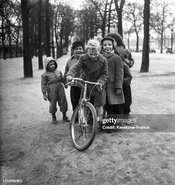 Enfant à vélo jouant à la course des Six jours dans le jardin des Champs-Elysées, le 2 mars 1951, à Paris.