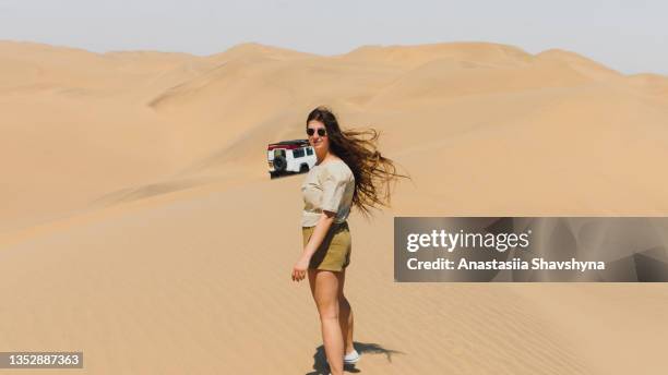 woman traveler enjoying a day at the sand dunes by the sea with 4x4 car in namibia - walvis bay stock pictures, royalty-free photos & images