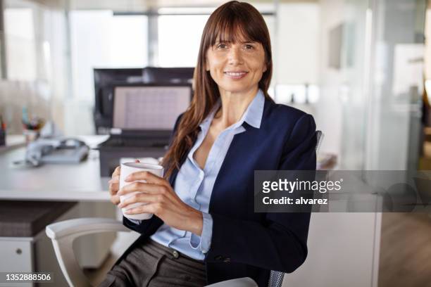 portrait of a business woman having a coffee break in office - creative director stock pictures, royalty-free photos & images