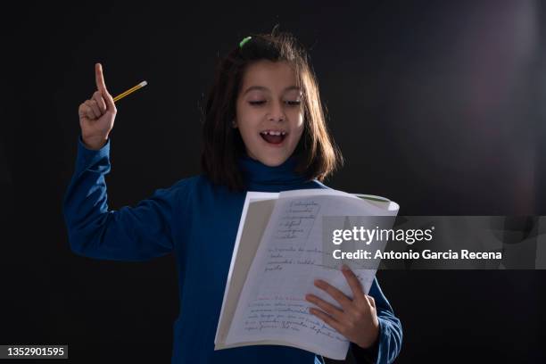 girl on black background studio shot, she holds a notebook with notes and can symbolize acting, learning, homework ... - actor studio shot stock-fotos und bilder