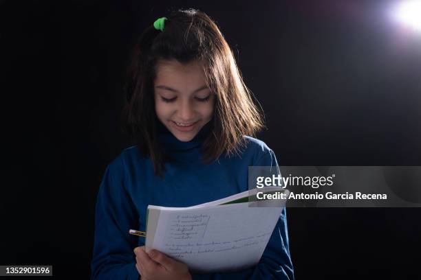 girl on black background studio shot, she holds a notebook with notes and can symbolize acting, learning, homework ... - man acting being shot stock-fotos und bilder