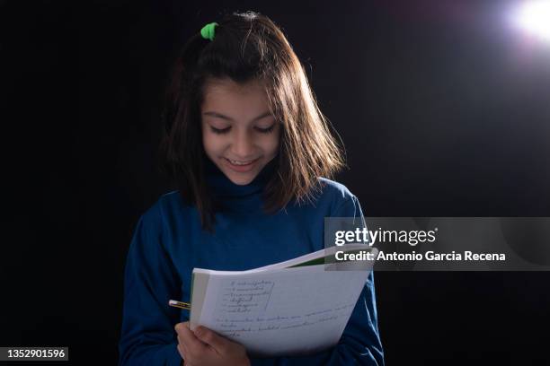 girl on black background studio shot, she holds a notebook with notes and can symbolize acting, learning, homework ... - actuación representación fotografías e imágenes de stock