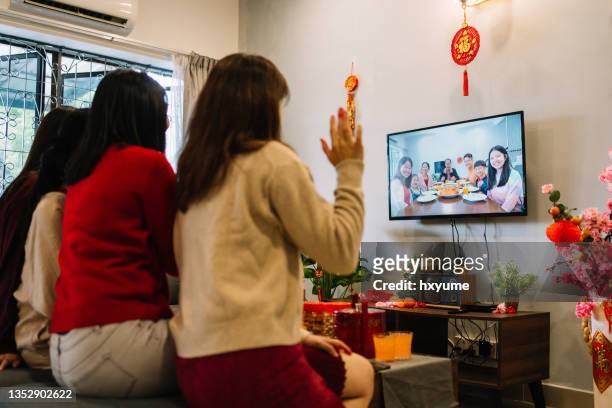 chinese new year gathering using video call on smart tv in living room - smart tv living room stock pictures, royalty-free photos & images