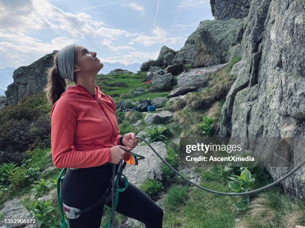 woman belays climber in rugged environment - zekeren stockfoto's en -beelden