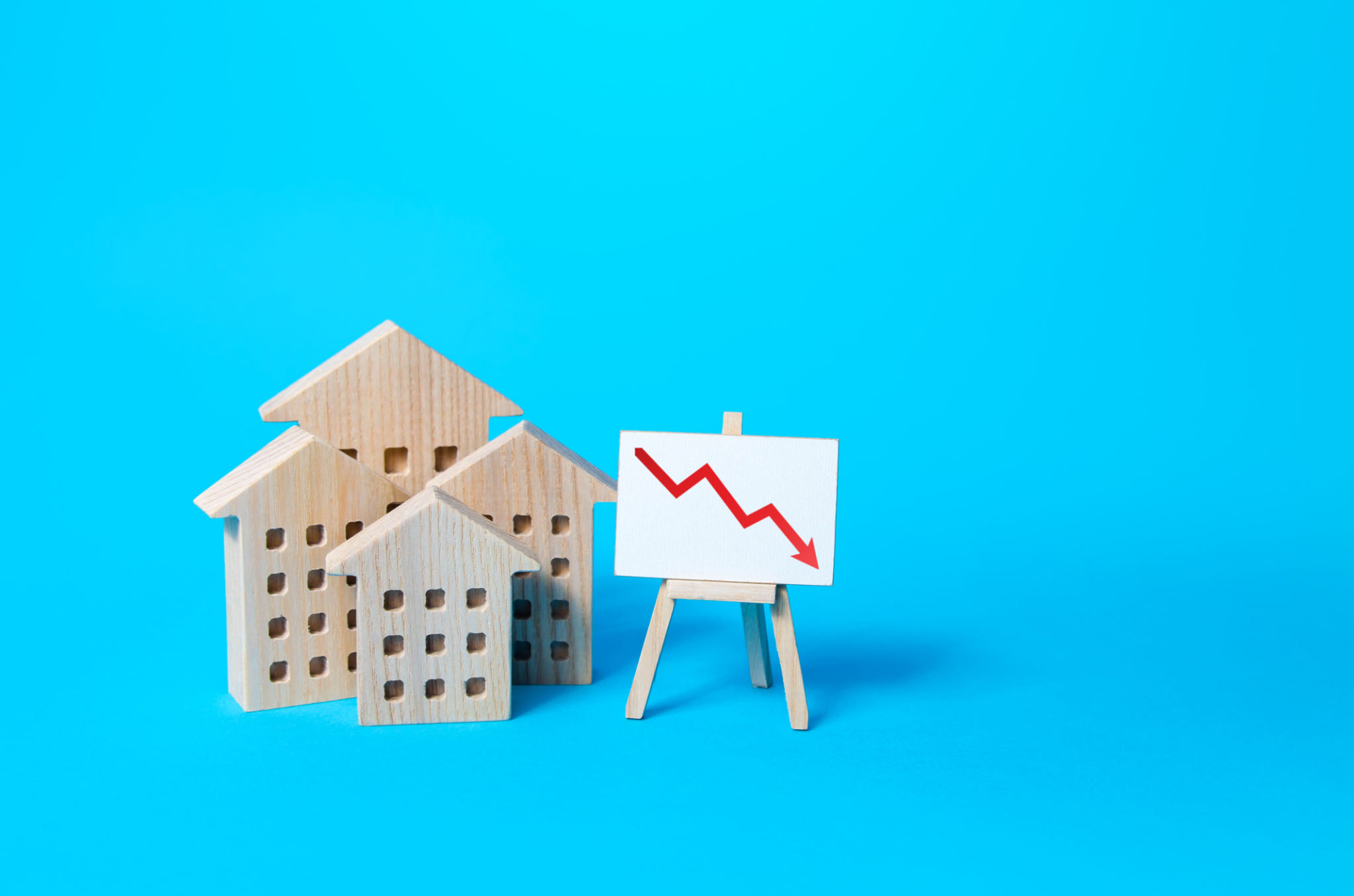 Residential buildings and down arrow graph on easel. Low property value, low price. Real estate market fall. Lower mortgage interest rates. Falling prices for rental. Affordable housing. Crisis Residential buildings and down arrow graph on easel. Low property value, low price. Real estate market fall. Lower mortgage interest rates. Falling prices for rental. Affordable housing. Crisis