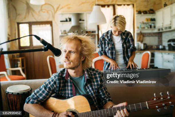 a musician playing guitar and singing together with a piano player at home - gig living room stock pictures, royalty-free photos & images