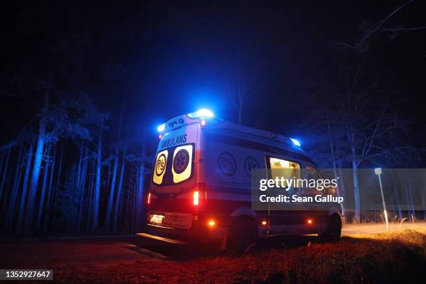 The lights of an ambulance, where inside medics were treating a Kurdish woman for hypothermia, flash on a road as it stands in a forest on November...