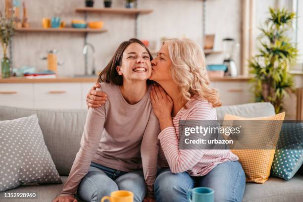 mother kissing her adult daughter on the cheek - cheek kiss stock pictures, royalty-free photos & images