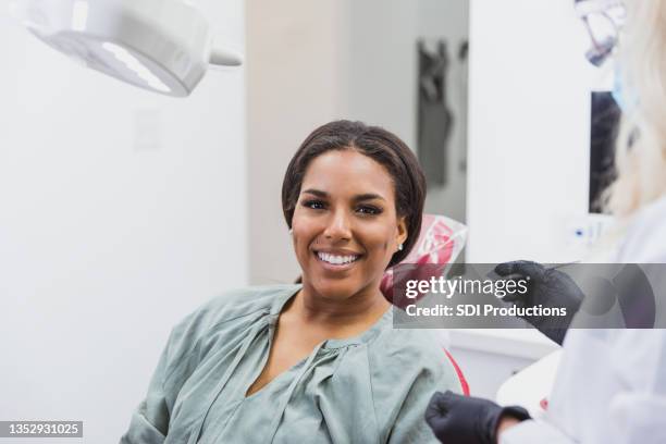 woman smiles during dental appointment - dental equipment stockfoto's en -beelden