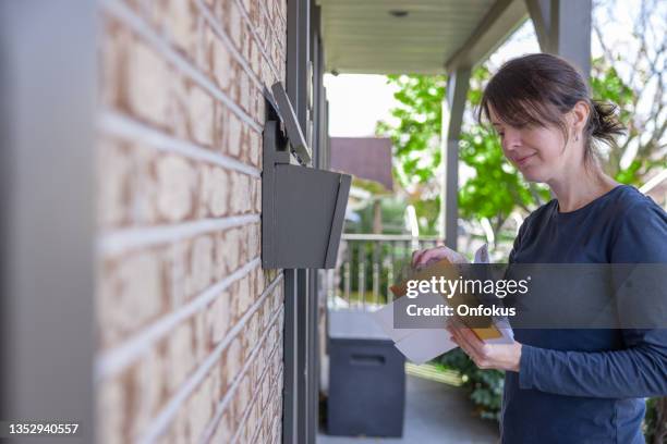 mujer recogiendo correo en casa en su buzón en australia - ranura de buzón fotografías e imágenes de stock