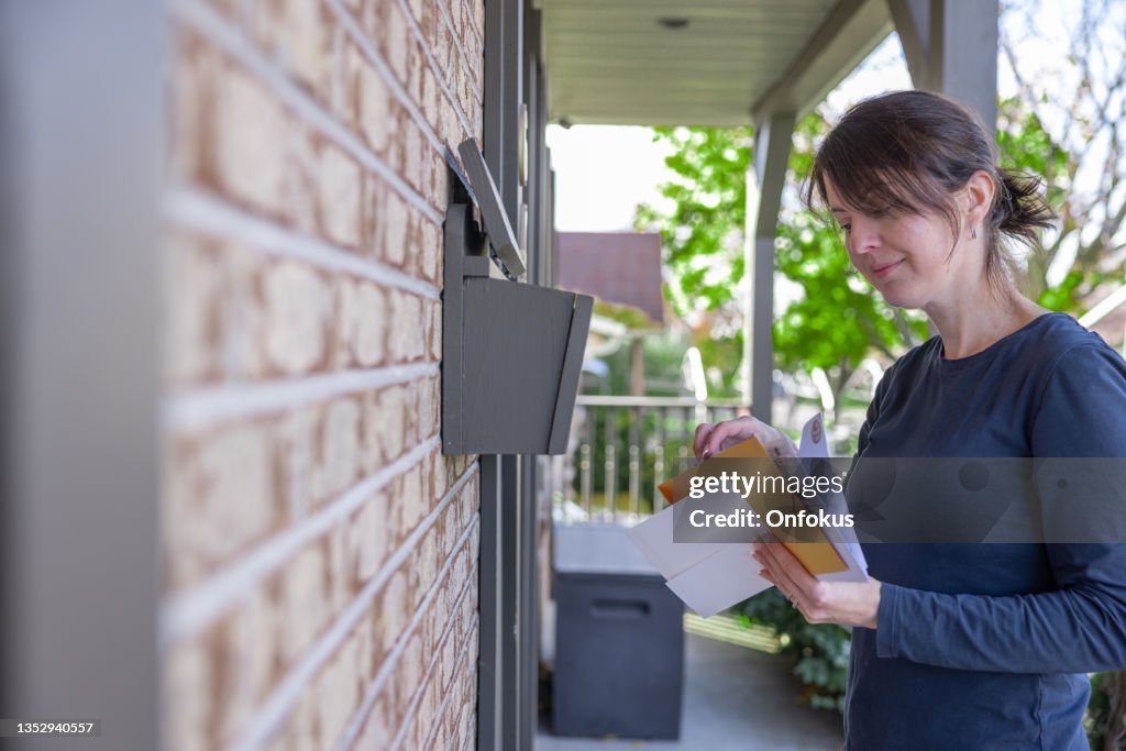 オーストラリアのメールボックスで自宅でポストを収集する女性