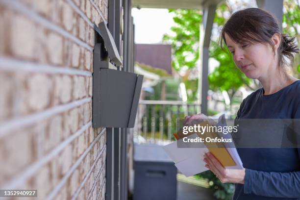 woman collecting post at home in her mailbox in australia - debt collector stockfoto's en -beelden