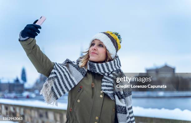 woman taking selfie near frozen river - one embankment stock-fotos und bilder