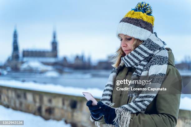 female using smartphone in winter - one embankment stock-fotos und bilder