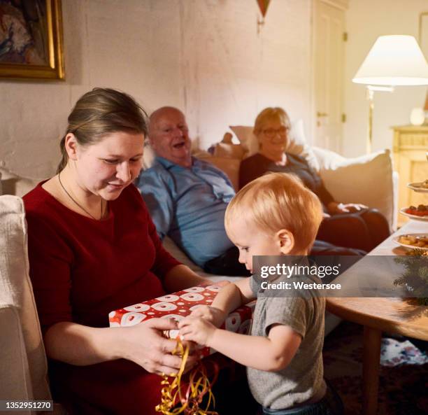 mother and child unwrapping christmas present - christmas scandinavia stock pictures, royalty-free photos & images