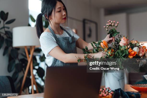 young woman arranging flowers while doing online workshop - florist arranging stock pictures, royalty-free photos & images