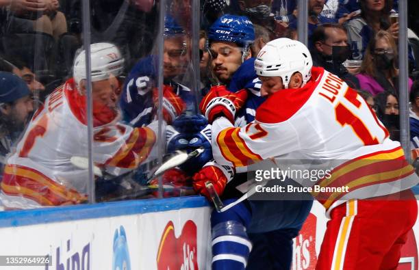 Milan Lucic of the Calgary Flames runs Auston Matthews of the Toronto Maple Leafs into the boards during the first period at the Scotiabank Arena on...