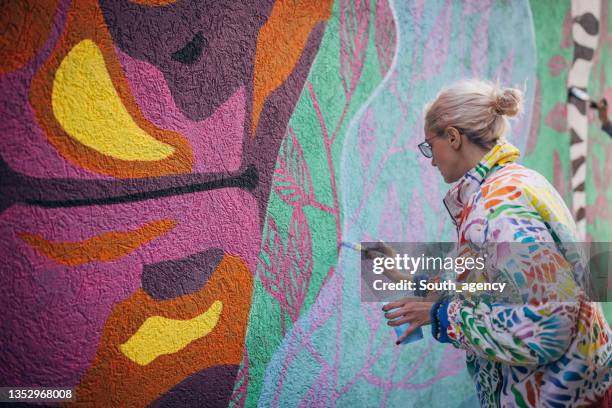 artista femenina pintando en la pared - pintor fotografías e imágenes de stock
