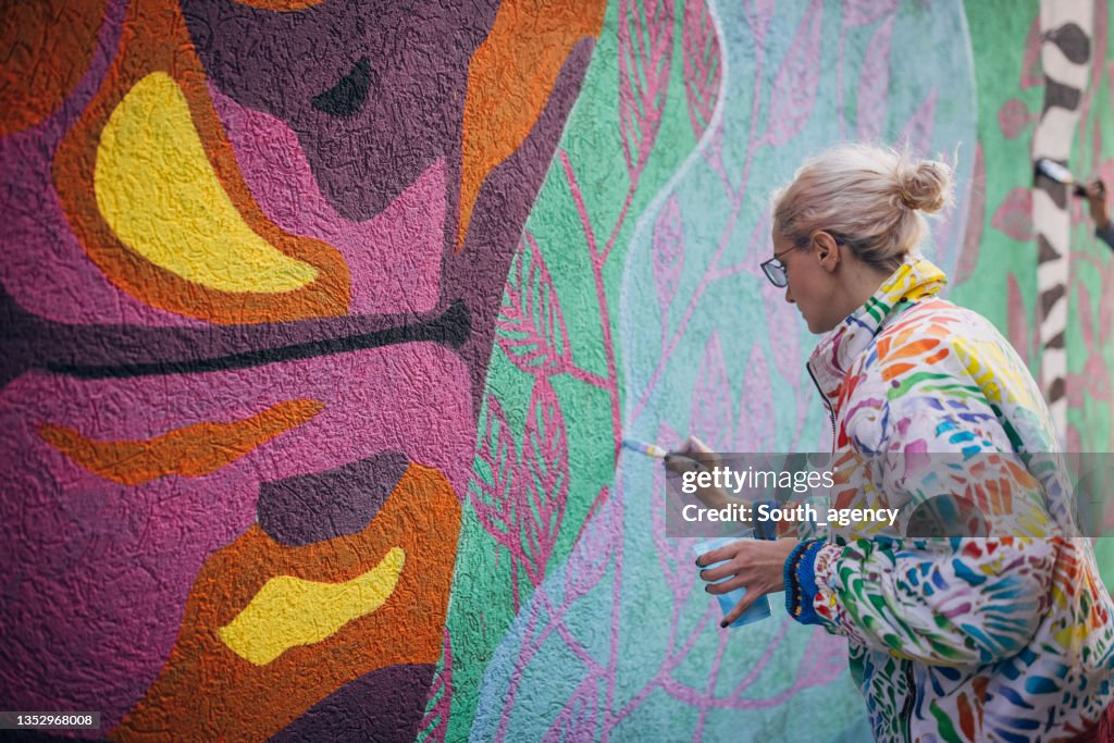 Female artist painting on wall