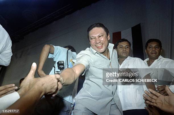 This photo taken on February 12, 1988 in Panama City shows General Manuel Antonio Noriega reaching down to shake hands of followers who attended...