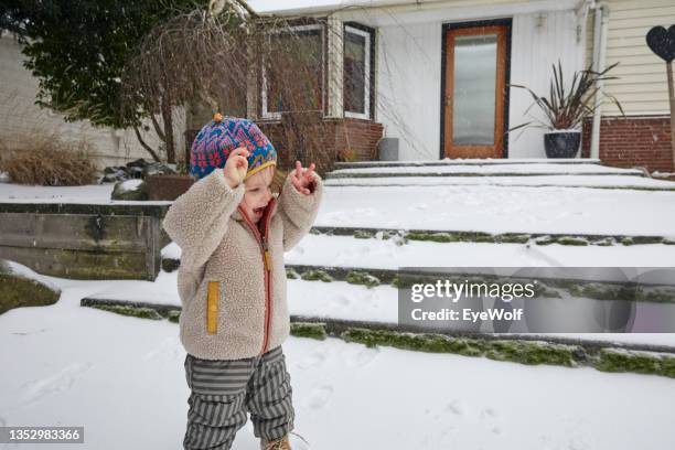 a toddler raising arm in excitement, experiencing snow for the first time. - erstereignis stock-fotos und bilder