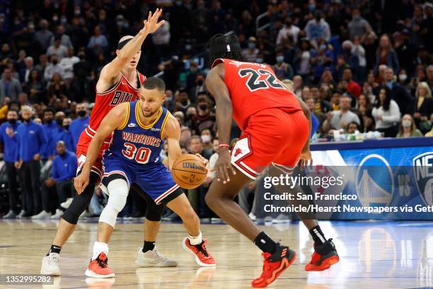 Golden State Warriors guard Stephen Curry drives towards the basket as Chicago Bulls guard Alex Caruso and forward Alize Johnson defends during the...