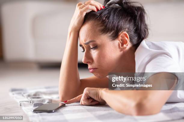 unhappy woman touches her phone with a finger desperately awaiting a call from someone. - waiting stock-fotos und bilder