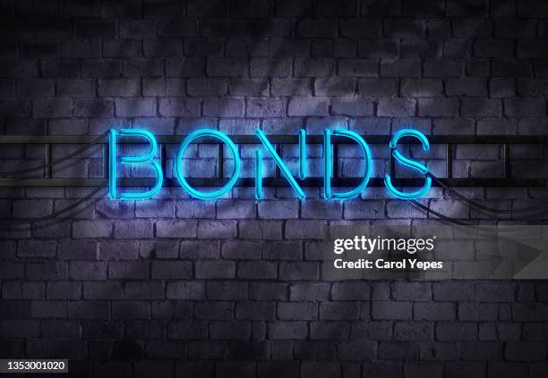 bonds word in neon lights against brick wall - bonds finance stockfoto's en -beelden