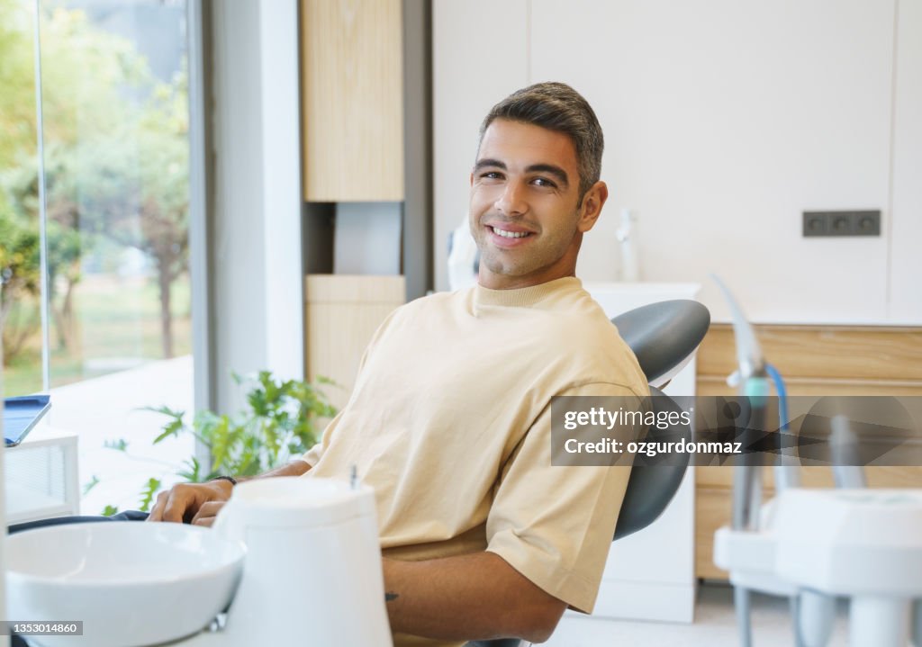 Portrait of happy young man sitting in a dentist’s chair