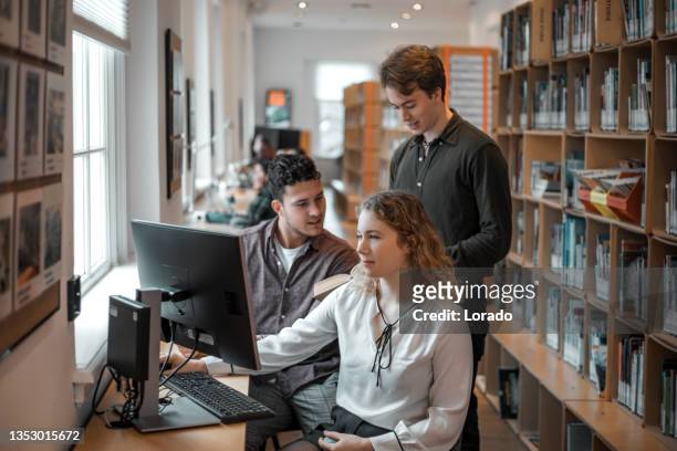 three university students working together in a public library - linguistics stock pictures, royalty-free photos & images