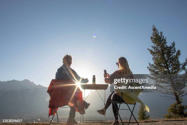 couple enjoy hot beverage on a mountain ridge at sunset - sun flare couple stockfoto's en -beelden