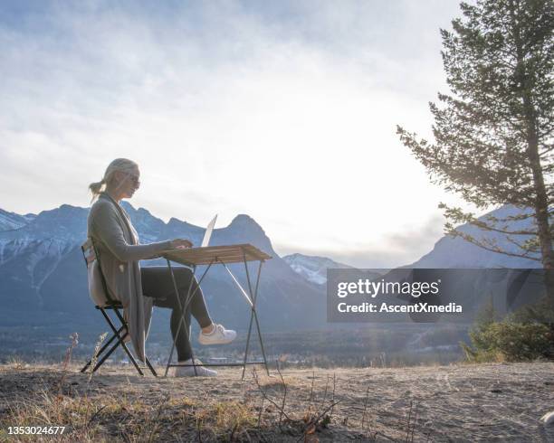 woman works remotely on a mountain ridge at sunrise - working in remote location stock pictures, royalty-free photos & images