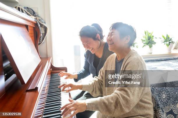 mother and daughter playing piano together - ピアノ ストックフォトと画像