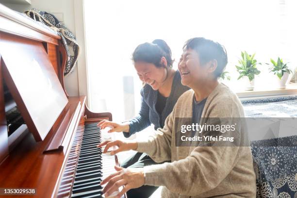 mother and daughter playing piano together - pianist stockfoto's en -beelden