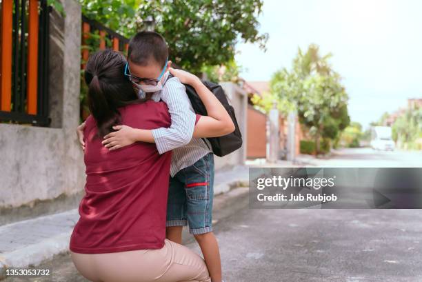 boy student running into mother's hands to hug her after back to school. - girls hands behind back stock-fotos und bilder