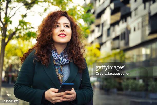 woman smiling with smartphone - nordafrikanischer abstammung stock-fotos und bilder