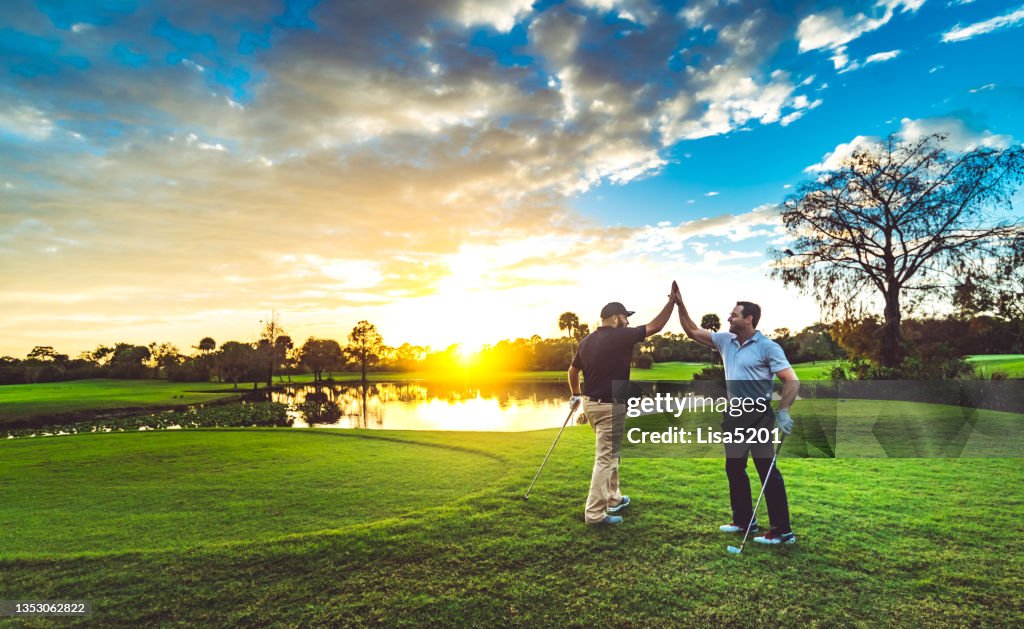 Zwei männliche Golfer High Five auf einem malerischen Golfplatz bei Sonnenuntergang