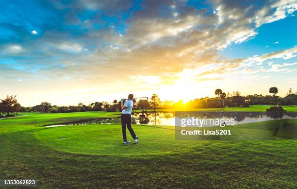 man on a beautiful scenic sunset golf course swings a golf club - west palm beach stock pictures, royalty-free photos & images