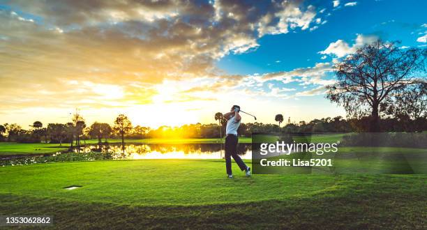 mann auf einem wunderschönen malerischen sonnenuntergang golfplatz schwingt einen golfschläger - golf spielen stock-fotos und bilder