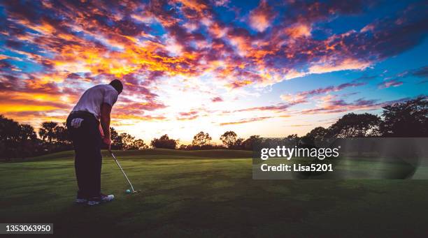 man on a idyllic scenic golf course putting at sunset, beauty in nature - golf swing sunset stock pictures, royalty-free photos & images